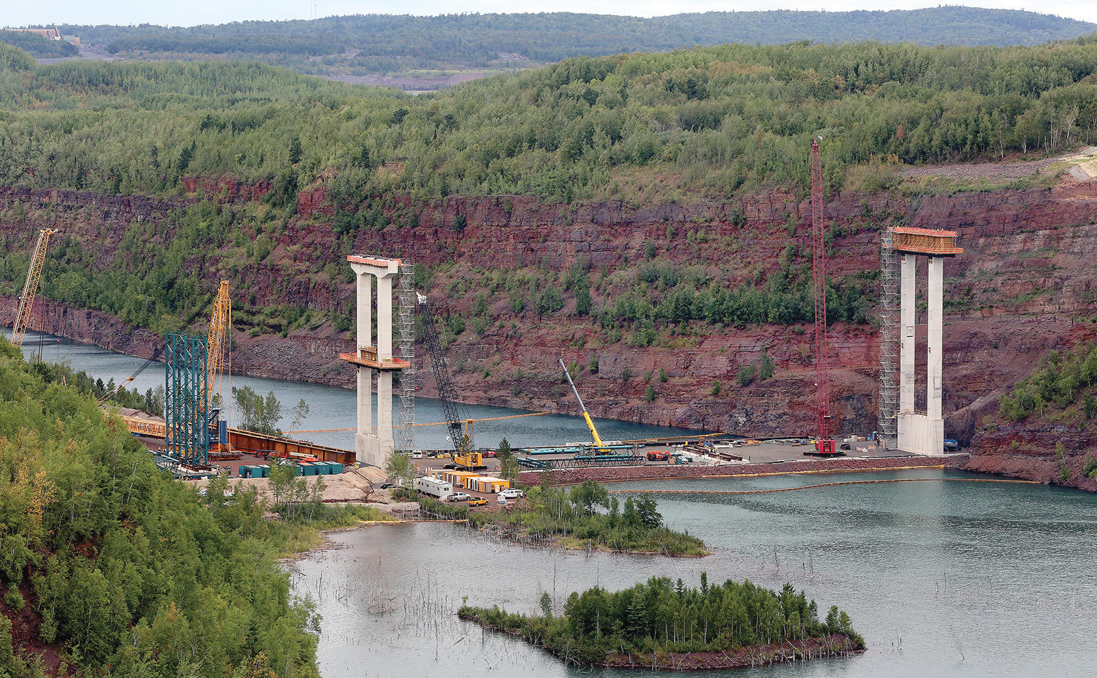 T08.24.2016 -- Steve Kuchera -- kucheraBRIDGE0827c3 -- The view from the location of the former Mineview in the Sky shows the concrete piers for the U.S. Highway 53 bridge being built across the Rouchleau pit rise above the pit’s water. The temporary metal framework (left) will help support metal beams when they are lifted into place. Workers will build a second temporary metal framework to right. Steve Kuchera / skuchera@duluthnews.com