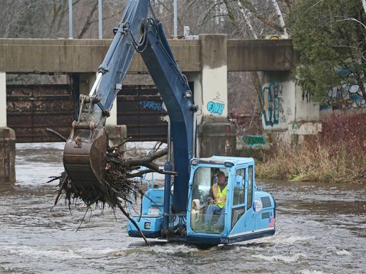 A DF Tomasini, Inc. excavator works to remove debris from the Milwaukee River